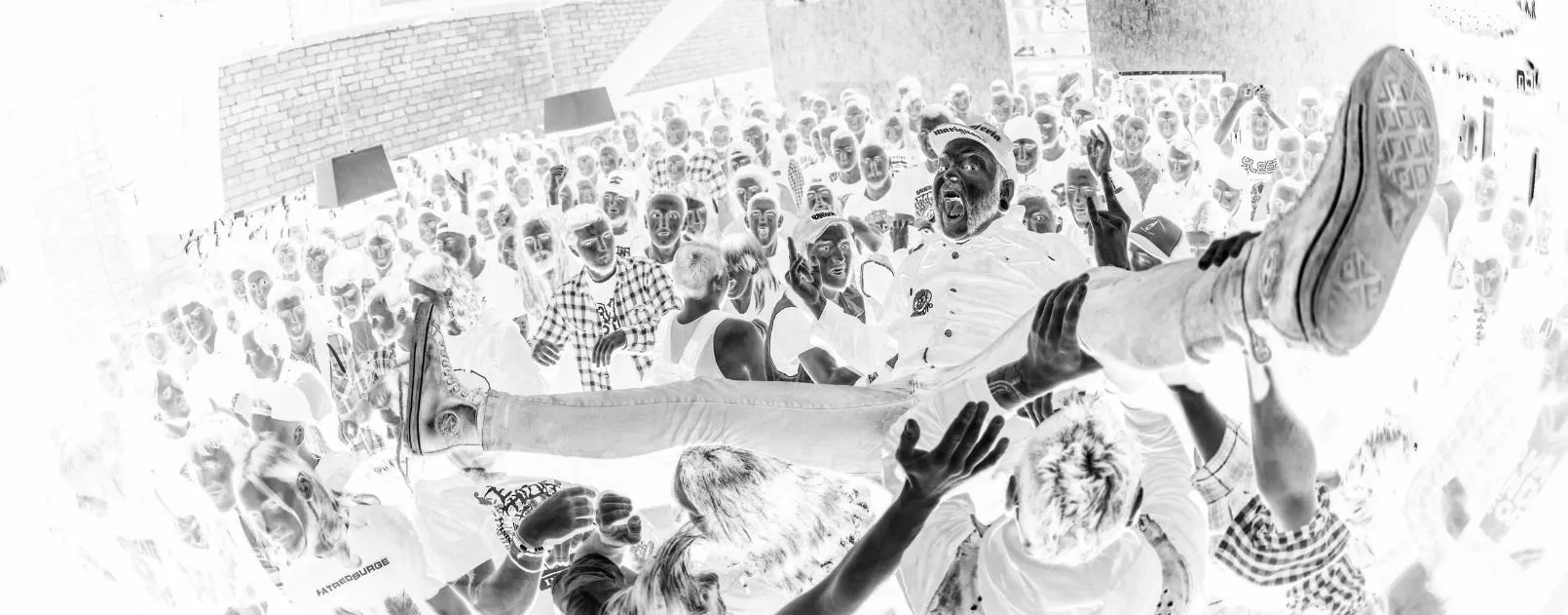 Crowd surfing at a concert, inverted black and white photo