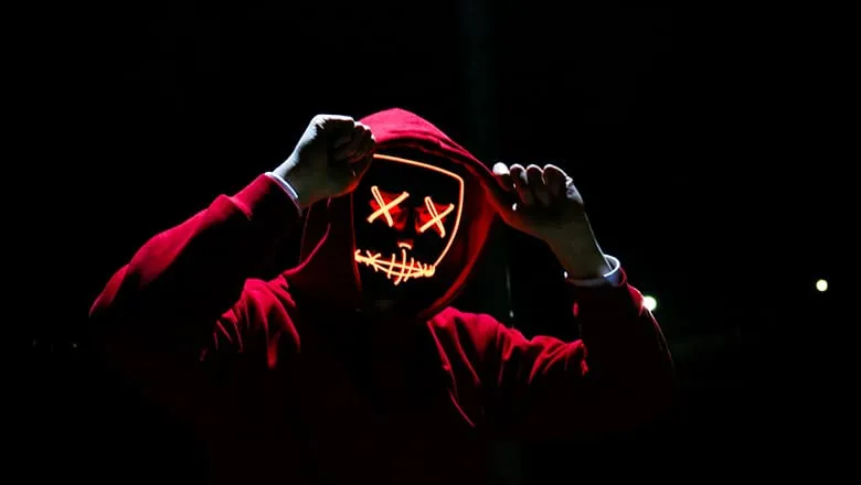 Person in a red hoodie wearing a glowing LED mask
