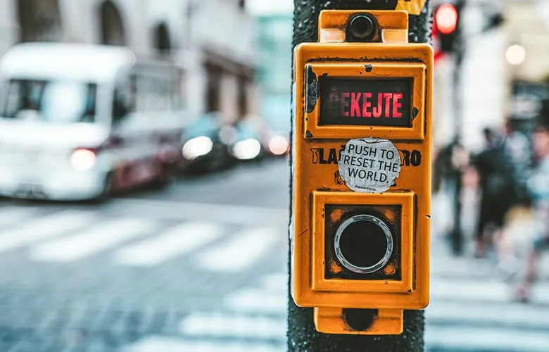 Traffic light push button with a sticker that reads “Push to reset the world”